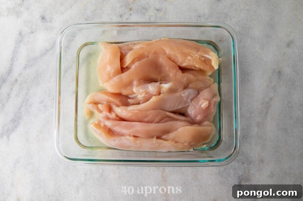 Chicken tenders marinating in pickle juice in a glass baking dish