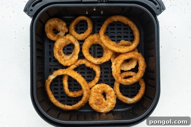 Frozen onion rings placed in a single layer in an air fryer basket.