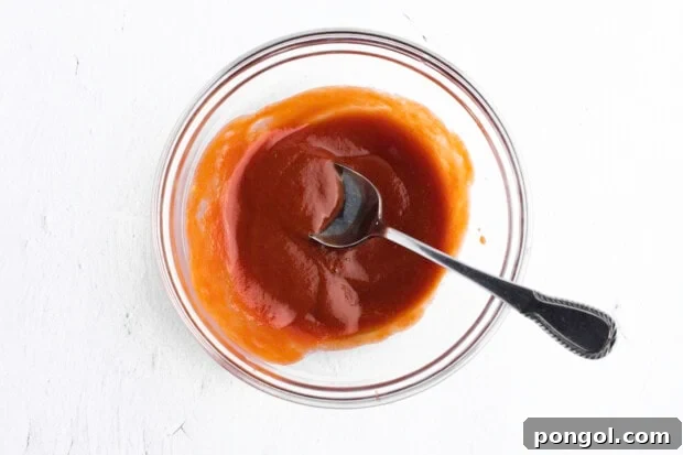Paleo-friendly ketchup glaze in large glass bowl with metal spoon