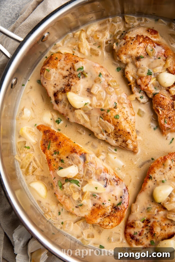Overhead view of Whole30 creamy garlic chicken in a large silver skillet, showcasing the golden-brown chicken cutlets and rich, creamy sauce.