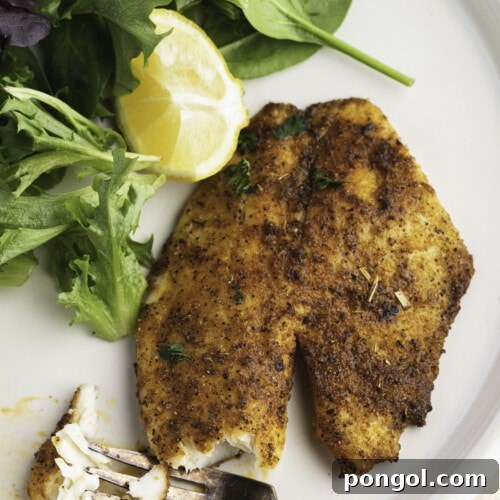 Golden Air Fryer Tilapia 4 Overhead view of air fryer tilapia on a plate with broccoli and a lemon wedge.