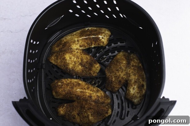 Golden Air Fryer Tilapia 8 Cooked tilapia fillets in air fryer basket.