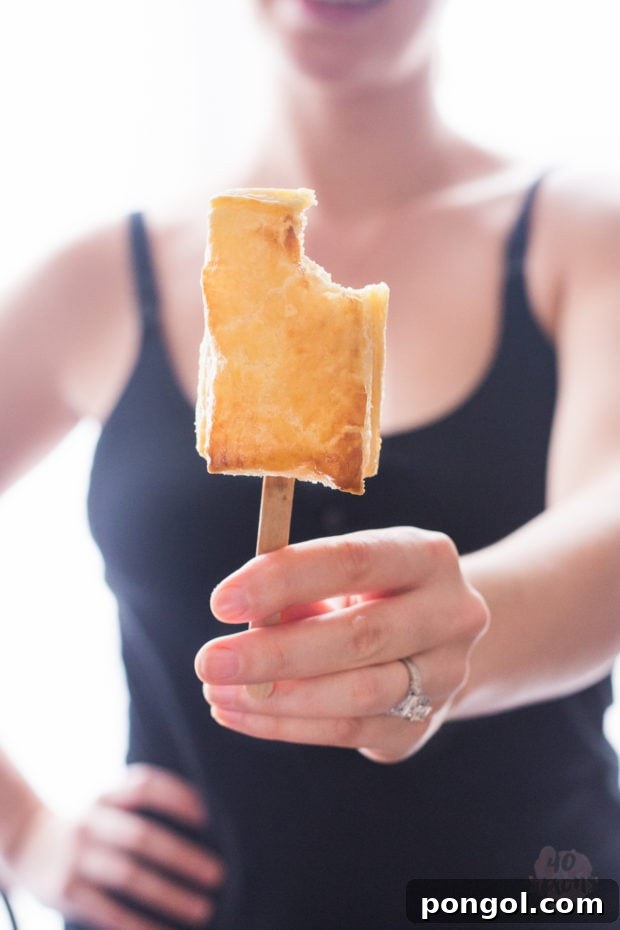 Close-up of a single baked brie bite with apricot jam, showcasing the rich texture and delicious filling.