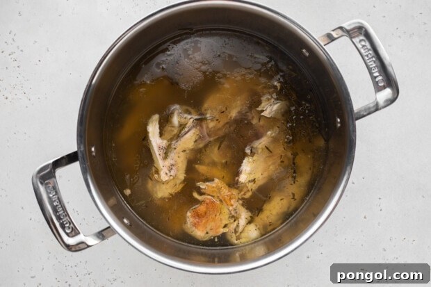 Bone broth gently simmering in a covered pot on the stove.