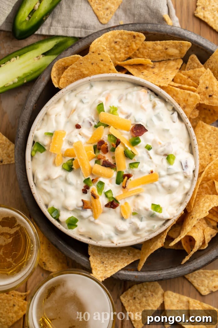 Overhead view of a bowl of jalapeno popper dip surrounded by tortilla chips