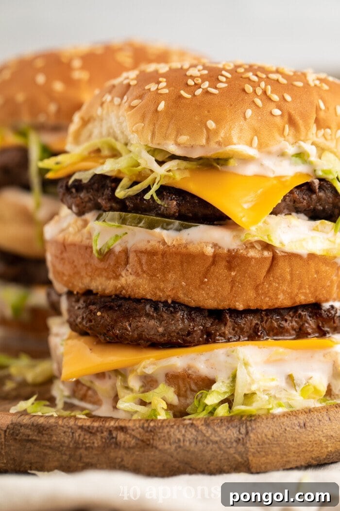A close-up view of a perfectly assembled Keto Big Mac, showing the stacked patties, melted cheese, fresh toppings, and special sauce.
