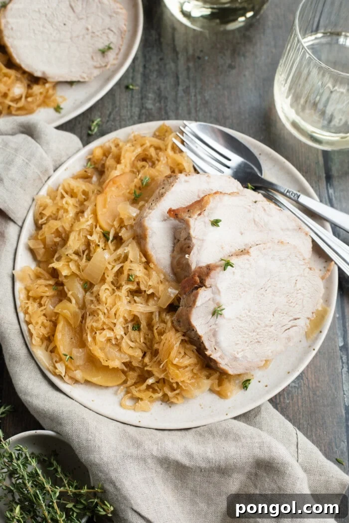 Hearty Pork and Kraut Comfort 2 sauerkraut and sliced pork roast on a plate with white wine on the side