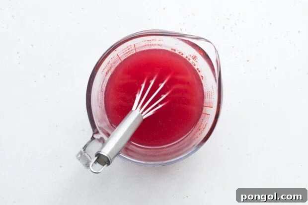 First step of making mango dragon fruit refresher: mixing all liquid ingredients and powder in a pitcher.