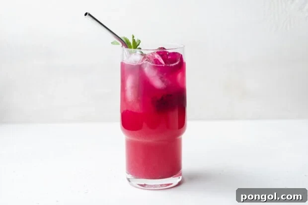 Second step of making mango dragon fruit refresher: pouring the mixed drink over ice and dragon fruit pieces in glasses.