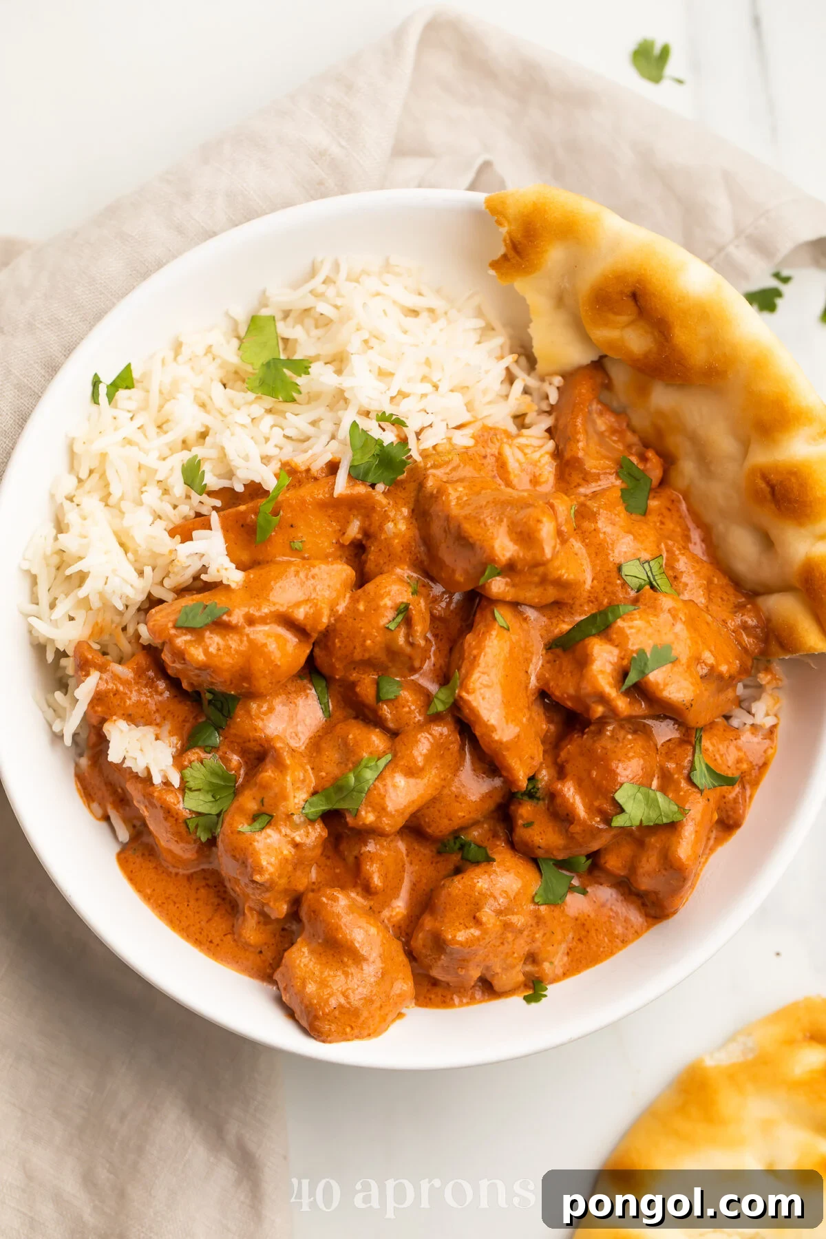 Velvet Butter Chicken 2 A vibrant, zoomed-out photo of rich red-orange butter chicken in a bowl, perfectly plated alongside fluffy white basmati rice and warm, golden naan bread, inviting a delightful meal.