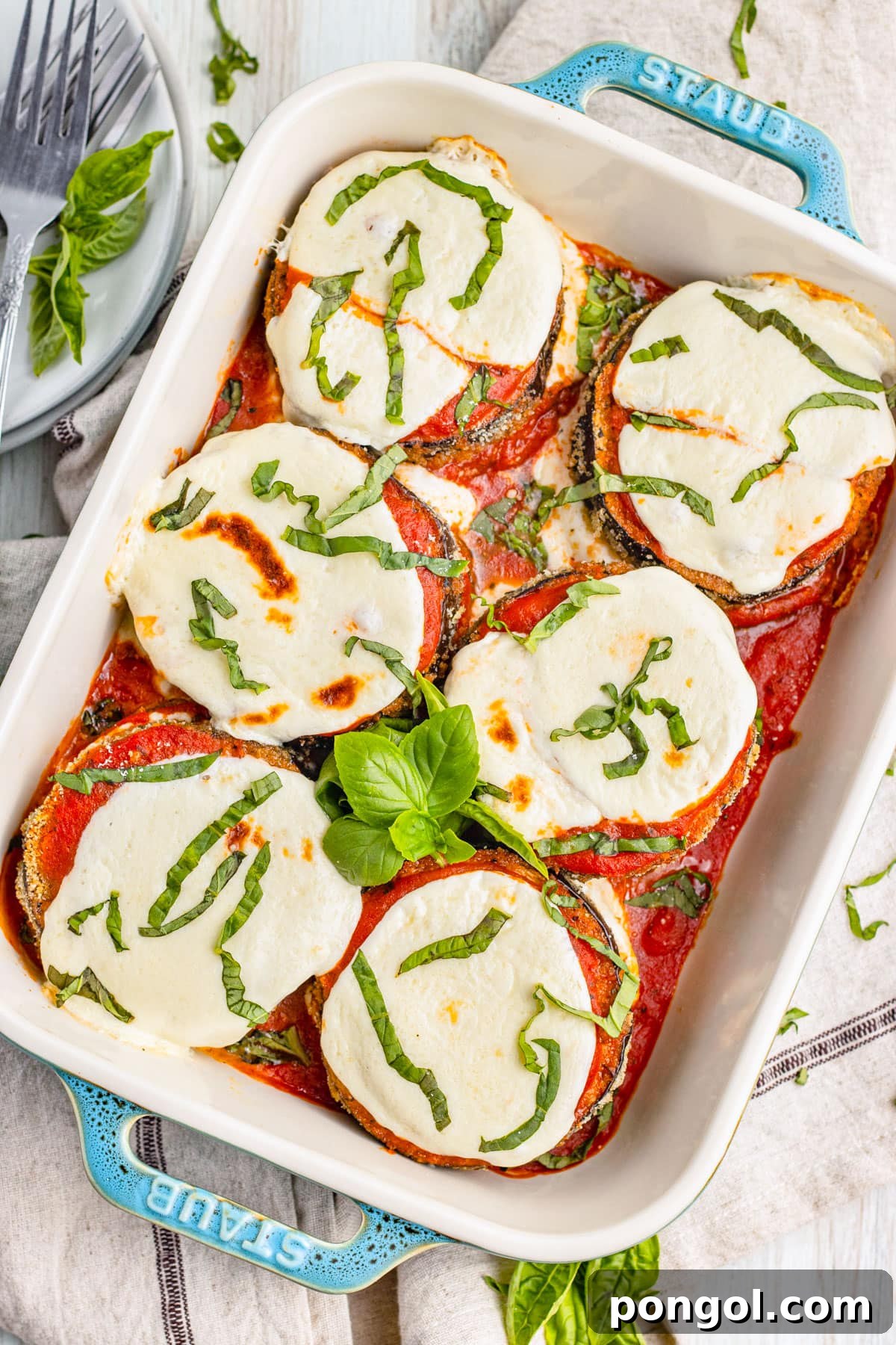Keto eggplant parmesan in a deep baking dish with turquoise handles.