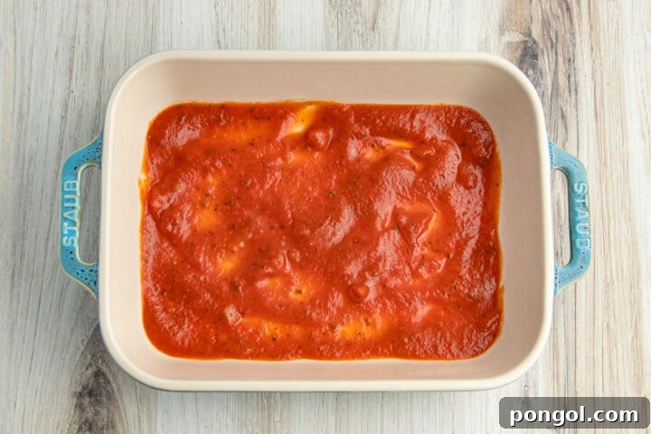 Keto-friendly red marinara sauce covering the bottom of a 9x13 baking dish.