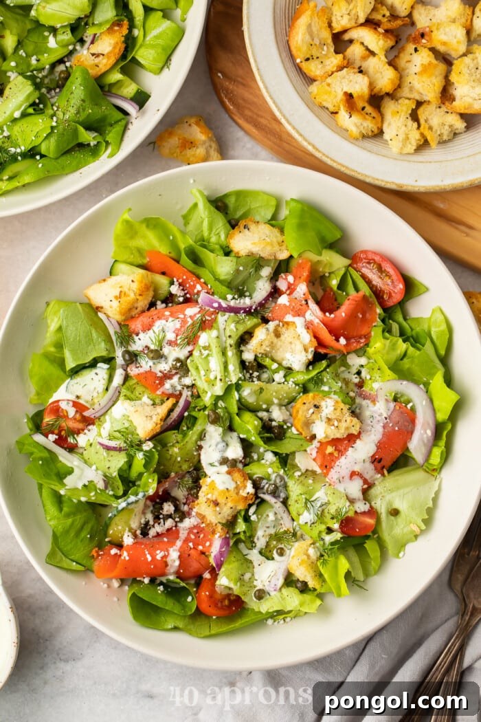 Smoked Salmon Bagel Bowl 2 Overhead view of a smoked salmon bagel salad in a white bowl with croutons in another bowl.