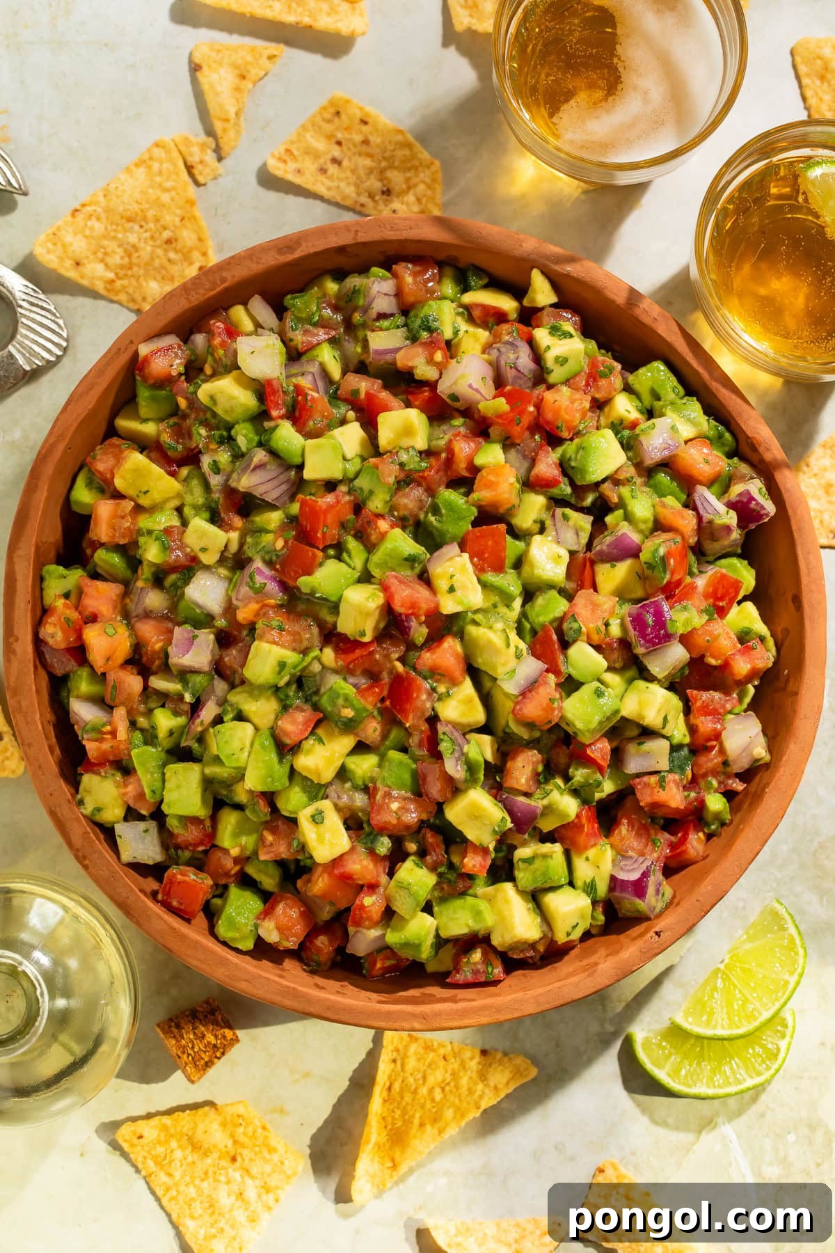 Chunky avocado tomato salsa in a wooden bowl with diced avocados, roma tomatoes, and red onion