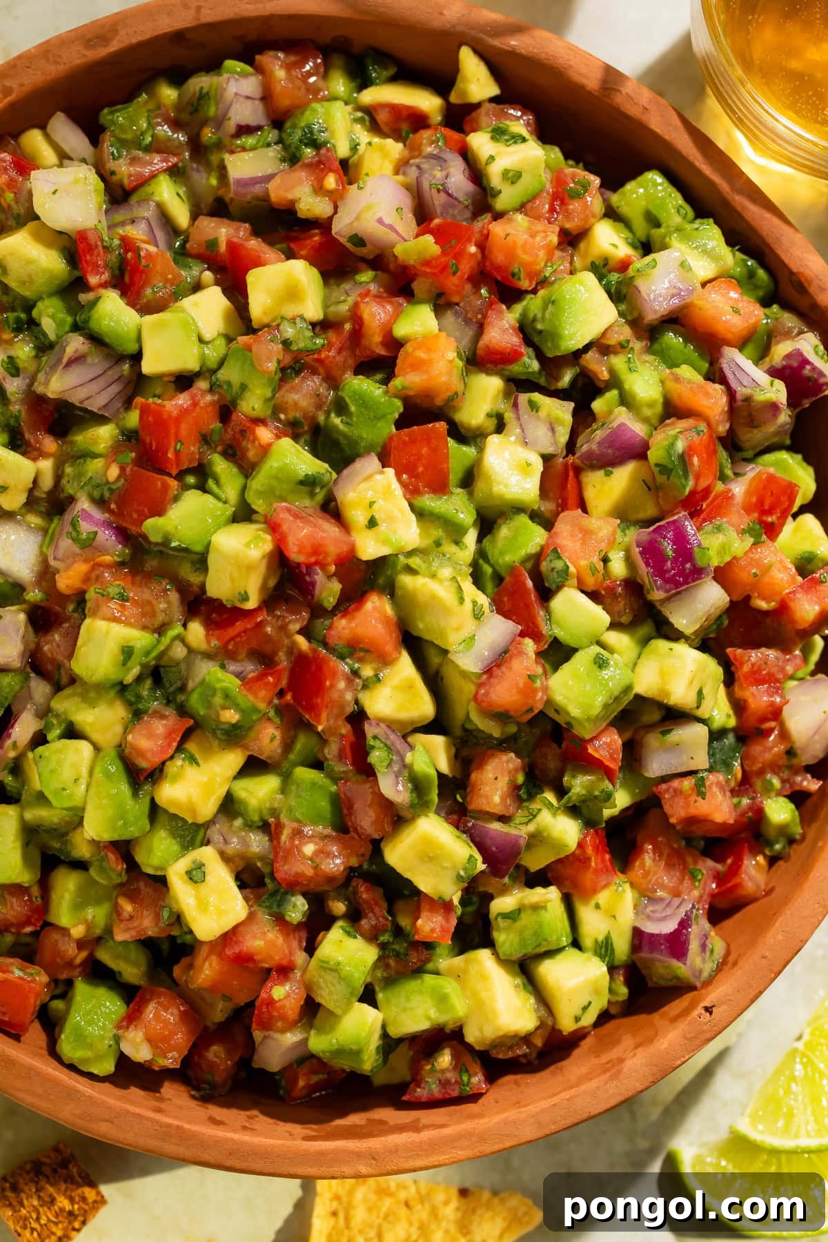 Avocado tomato salsa in wooden bowl showing chunky texture and fresh ingredients