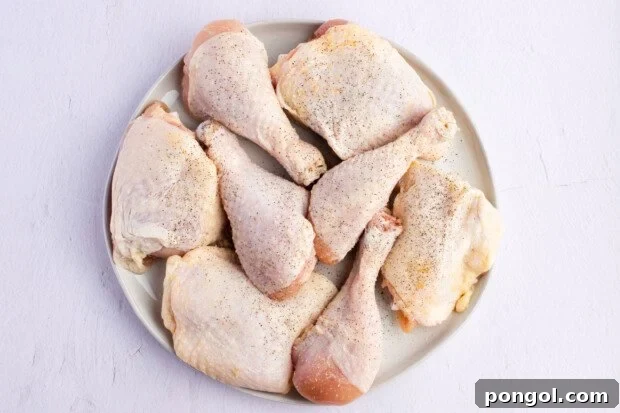 Raw, seasoned chicken thighs and drumsticks on a round plate.