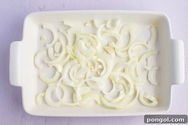 Onion slices lining bottom of a greased 9x13 baking dish.