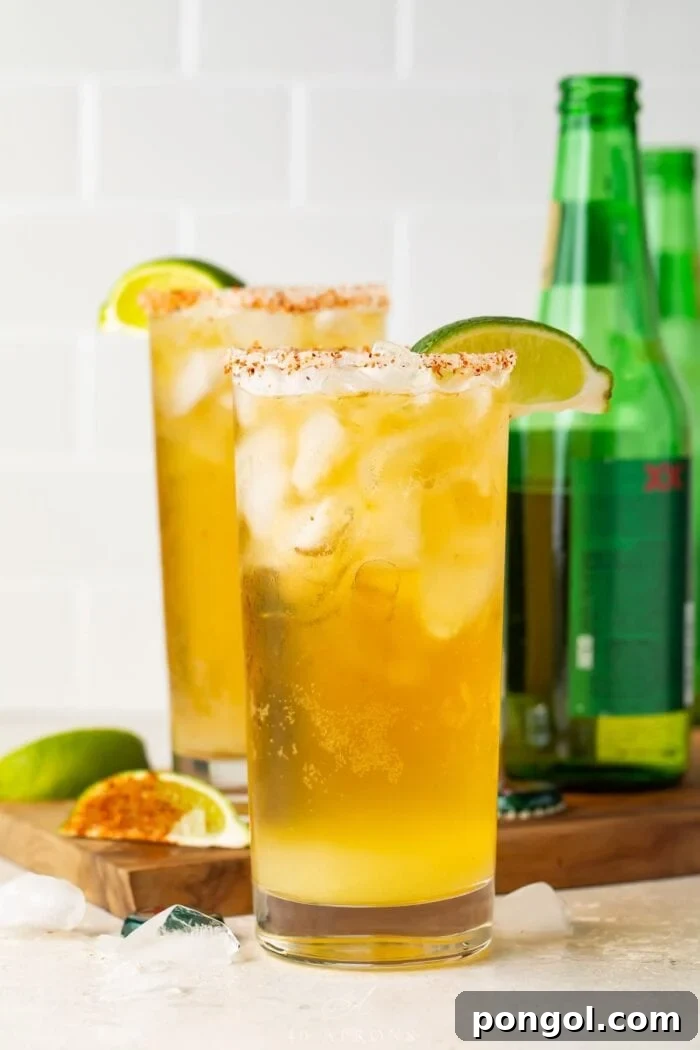 Chelada Zesty Mexican Beer with a Burst of Lime 2 Two tall salt-rimmed glasses of chelada in front of green beer bottles, inviting and refreshing.