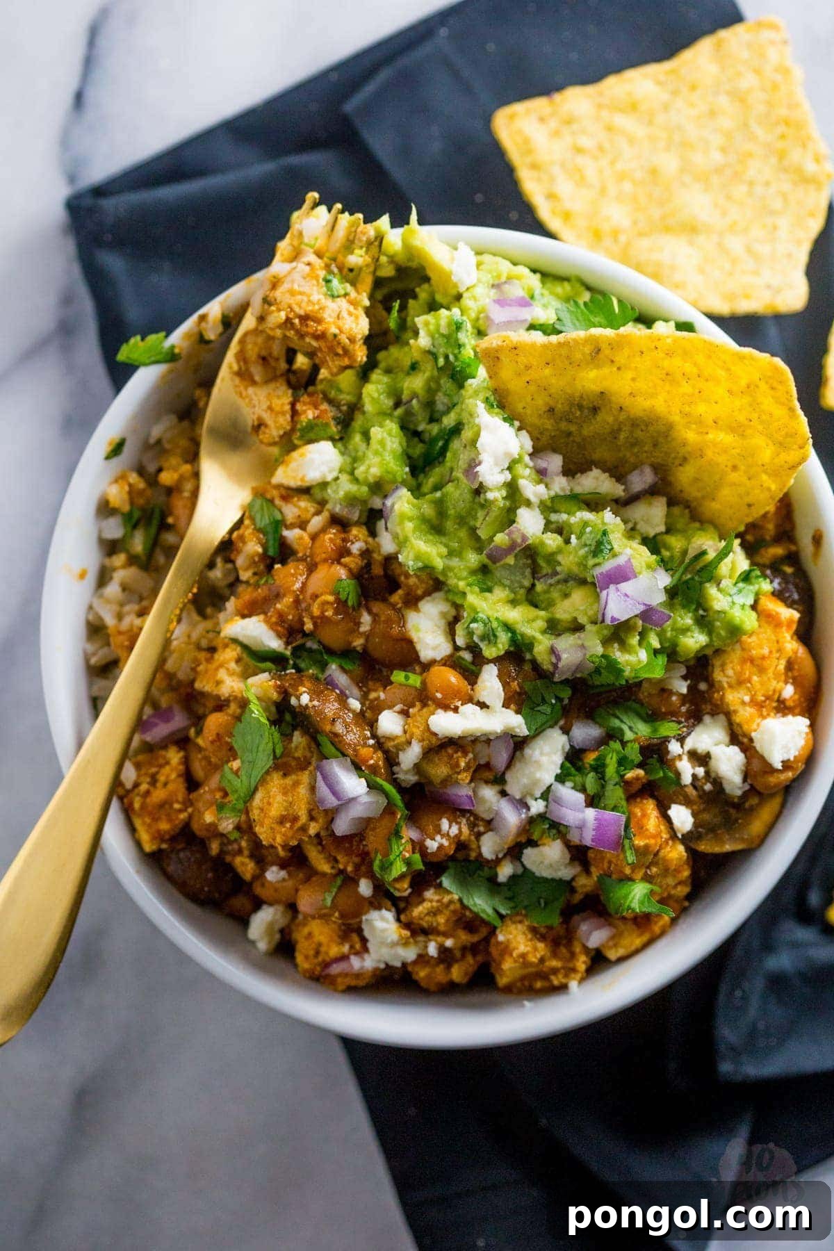 Hand scooping a spoonful of Tofu Sofritas into a bowl. | 40 Aprons