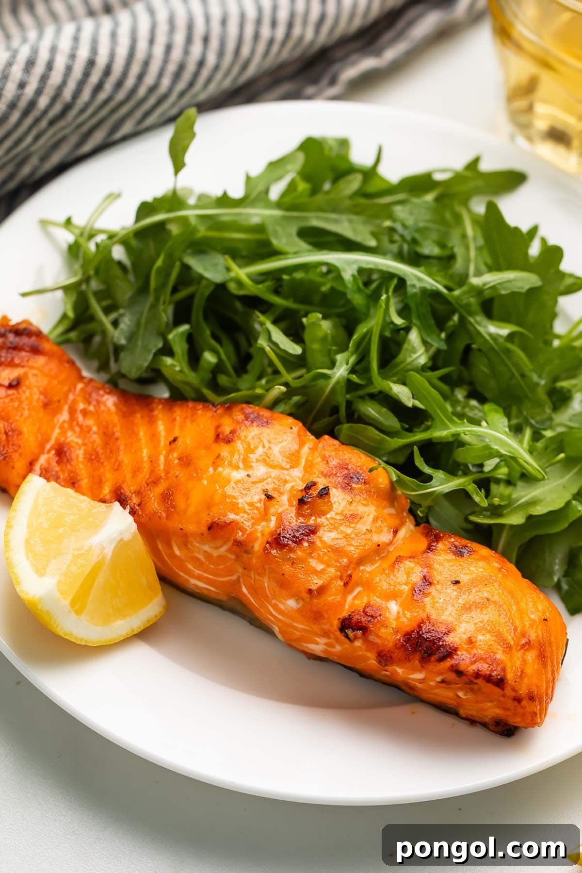 A previously-frozen salmon fillet cooked in the air fryer and served on a plate with a small side salad.