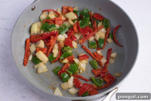 Red chilis, red bell peppers, green bell peppers, white onion, and ginger in large skillet.