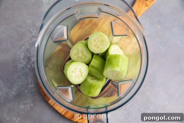 Peeled and chopped cucumbers in glass blender bowl.