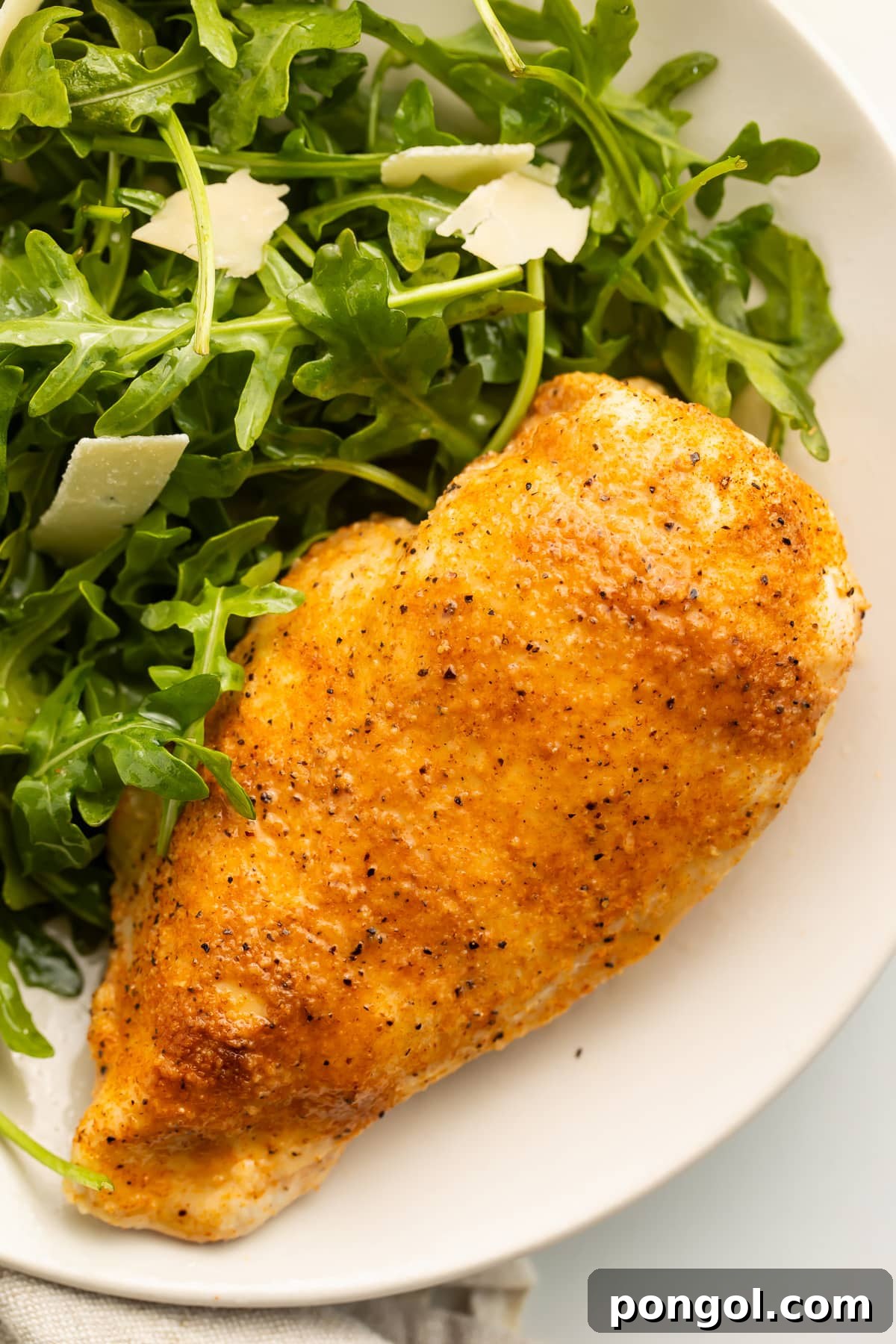 A whole Instant Pot chicken breast, fully cooked and resting on a plate with a small salad.