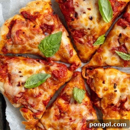 Close-up, angled view of soft and fluffy air fryer pizza on a white plate, ready to be enjoyed.
