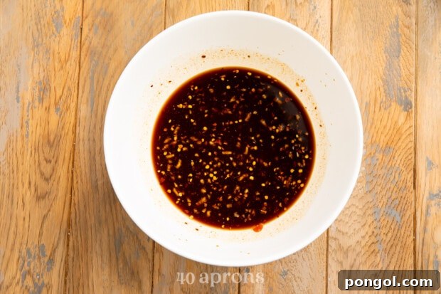Sticky Bourbon Glazed Chicken 6 Overhead view of a white mixing bowl with bourbon chicken sauce on a wooden table.