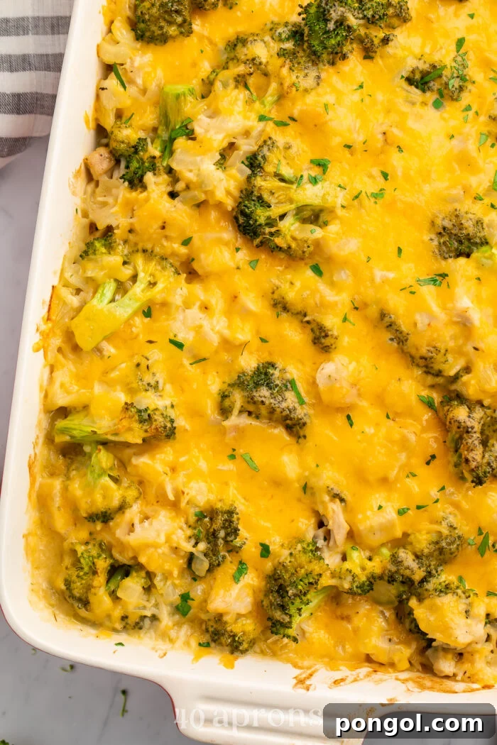 Overhead view of a white rectangular casserole dish angled from the top right corner of the image. Dish contains a baked chicken broccoli rice casserole, with steam gently rising.