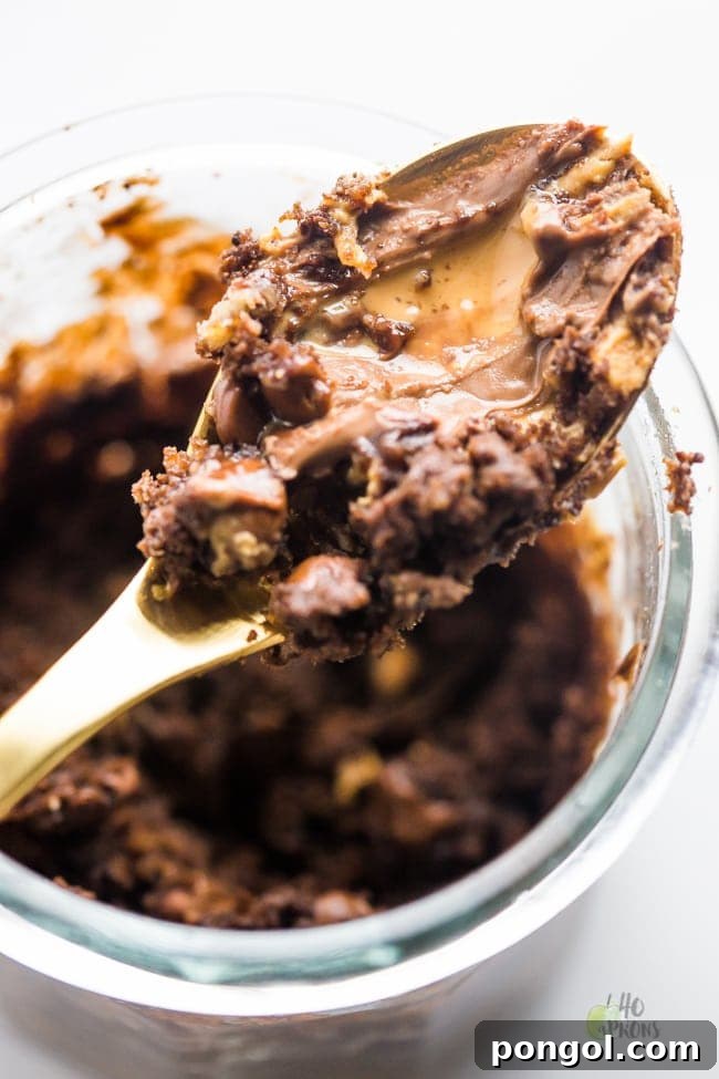 A close-up shot of the healthy chocolate peanut butter mug cake, showing its moist interior and gooey chocolate chips.