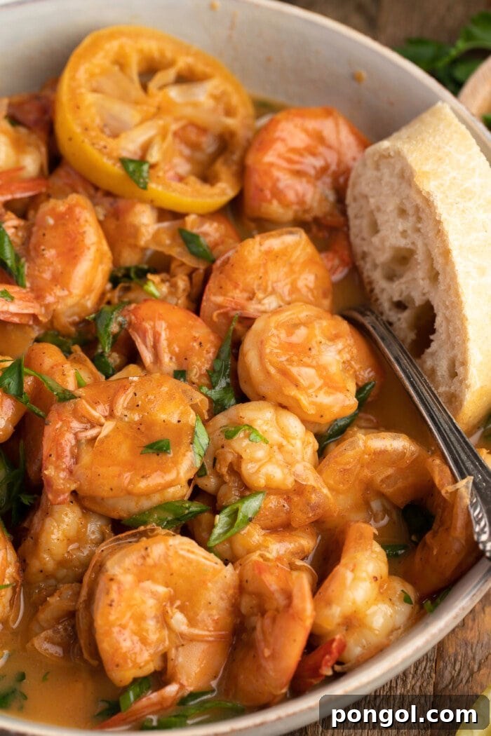 New Orleans Style BBQ Shrimp 2 Overhead view of a bowl of BBQ shrimp with crusty bread, ready to be served.
