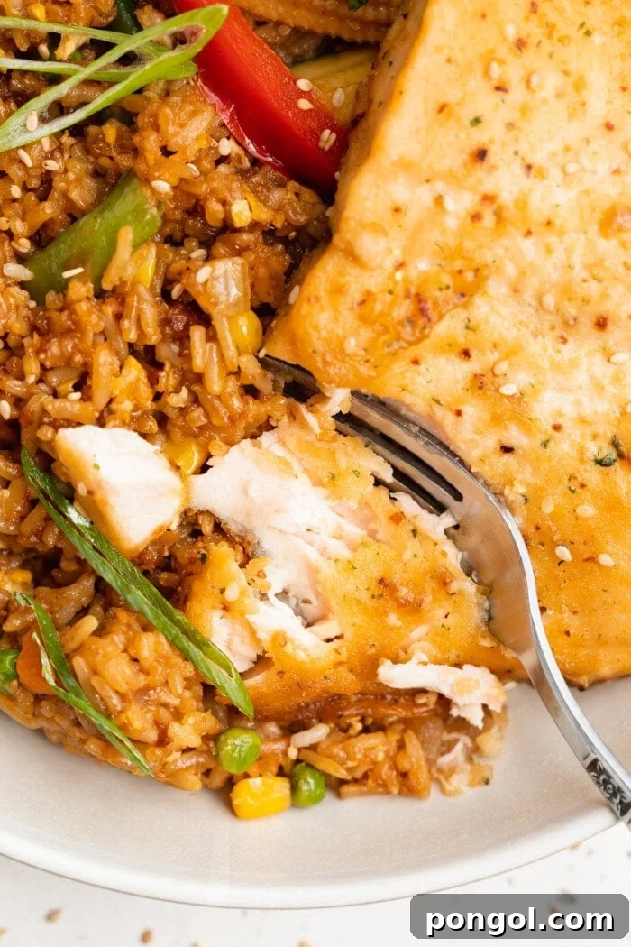 Close-up view of flaked teriyaki salmon with hibachi vegetables and fried rice, perfectly plated and ready to eat.