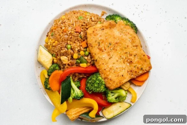 Overhead view of a beautifully plated teriyaki sesame salmon fillet, accompanied by hibachi fried rice and vibrant sautéed vegetables.