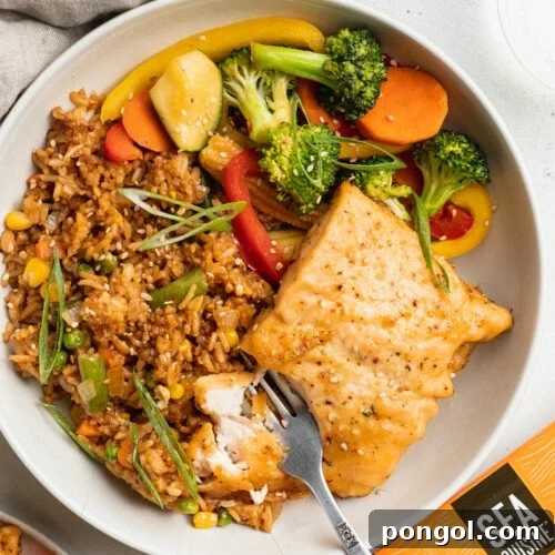 Overhead view of a beautifully plated teriyaki salmon hibachi dinner with fried rice and sauteed vegetables.
