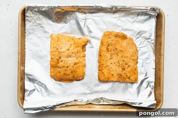 Two Sea Cuisine teriyaki sesame salmon fillets placed on a baking sheet lined with aluminum foil, ready for the oven.