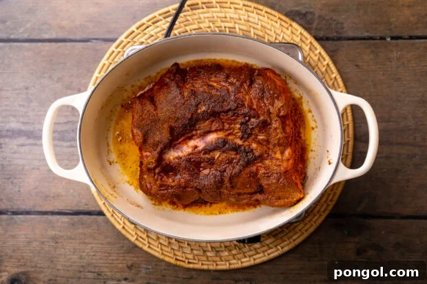 Overhead view of seasoned beef roast in a large pot with olive oil.