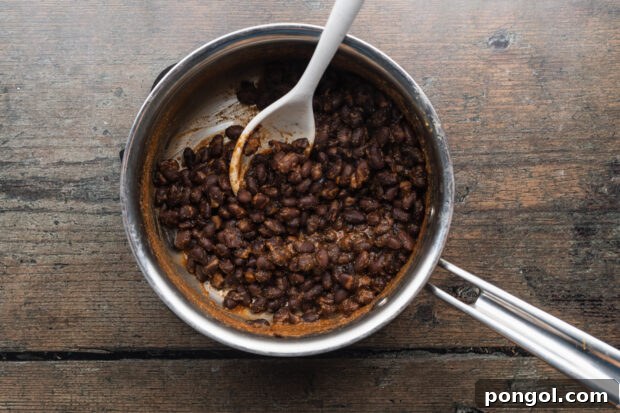 Tangy Beet Tacos 5 Overhead view of seasoned black beans in a large silver saucepan, ready for cooking.