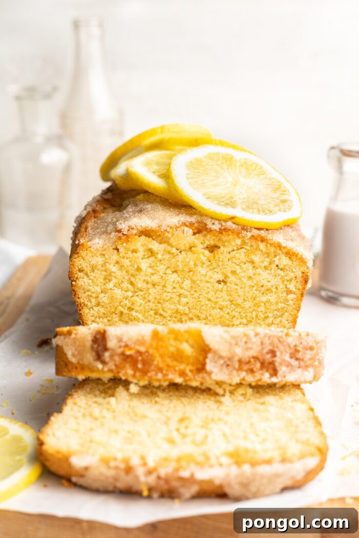 End-view of a perfectly baked gluten-free lemon drizzle cake with two slices cut, revealing its moist, airy texture and golden-brown crust.