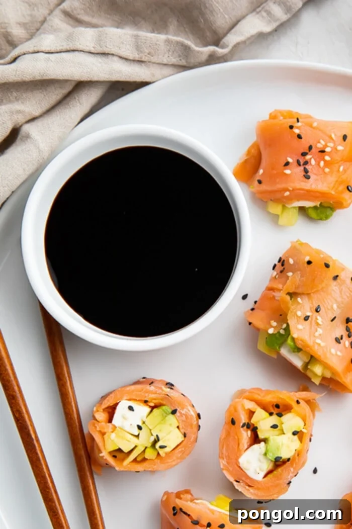 Overhead view of a bowl of soy sauce on a plate with smoked salmon sushi.