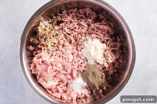 Overhead view of ingredients for Whole30 burgers in a large silver mixing bowl.