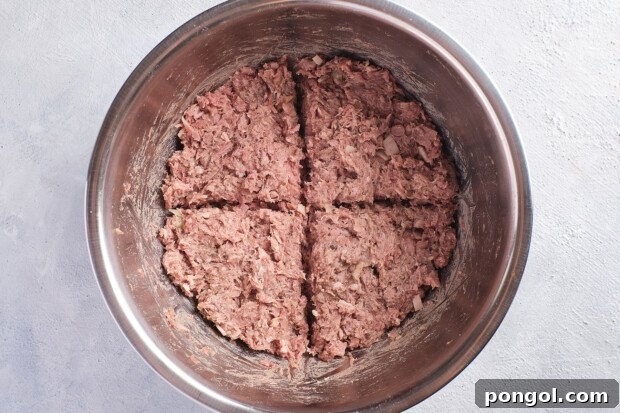 Overhead view of mixed Whole30 burger ingredients in a large silver bowl, divided into 4 sections.