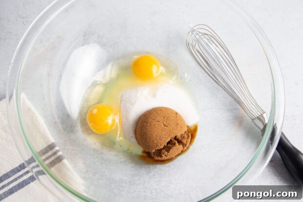 2 large eggs, brown sugar, and white sugar in large glass mixing bowl with whisk.