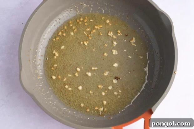 Overhead view of melted butter, minced garlic, and fresh lemon juice in a large skillet.