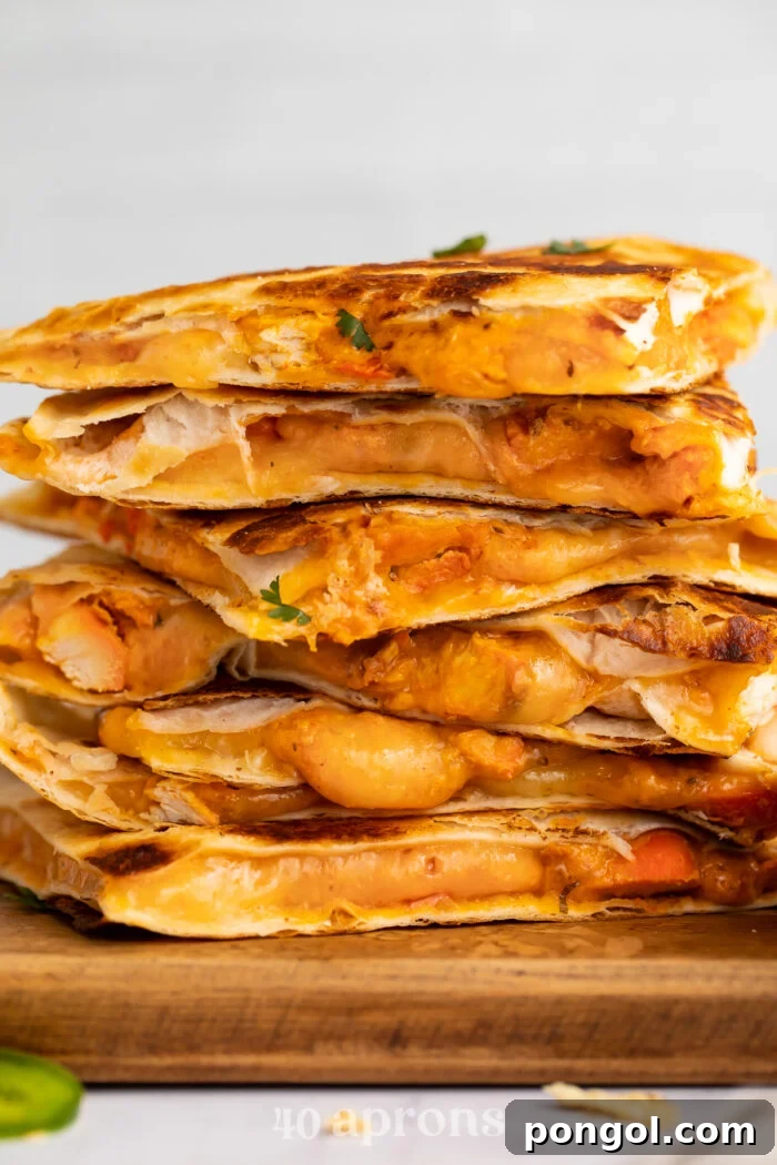 Spicy Tikka Masala Chicken Quesadilla 2 Side view of chicken tikka masala quesadillas stacked on top of each other, resting on a cutting board.