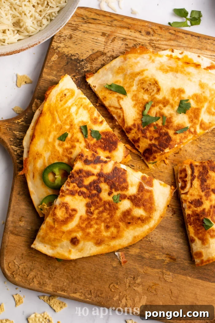 Spicy Tikka Masala Chicken Quesadilla 3 Chicken tikka masala quesadilla quarters on a wooden cutting board.