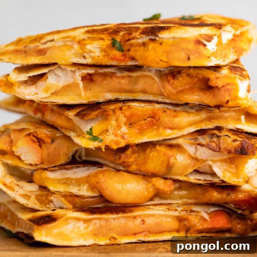 Spicy Tikka Masala Chicken Quesadilla 4 Side view of chicken tikka masala quesadillas stacked on top of each other, resting on a cutting board.