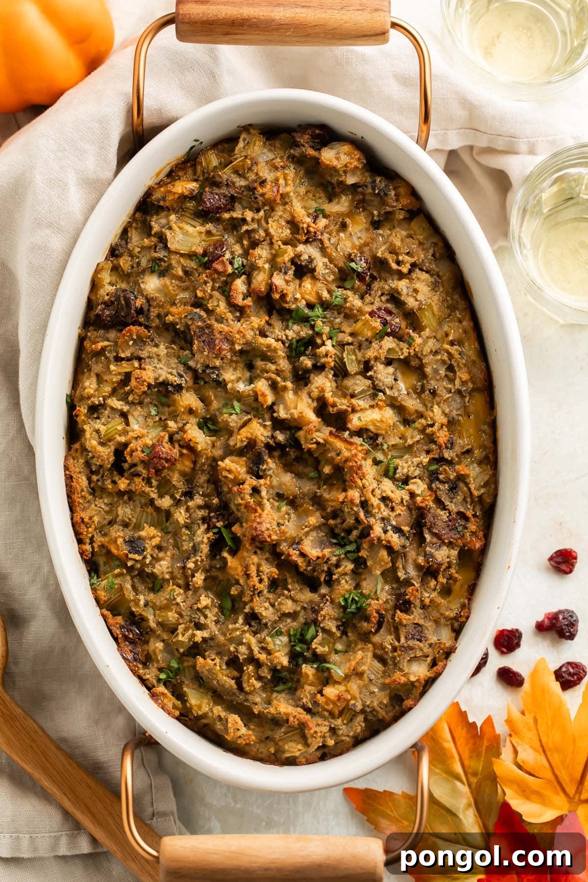 Wholesome Paleo Stuffing Grain Free 2 Top-down view of a large oval casserole dish holding a golden-brown paleo stuffing, made without any grains. It features visible pieces of onion, celery, mushrooms, and cranberries, all baked to perfection with slightly crisp edges, ready to be served on a holiday table.