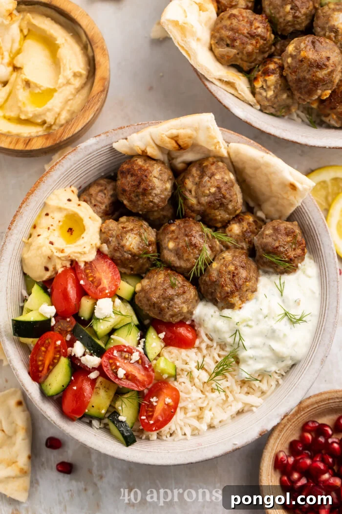 An overhead view of a vibrant Gyro Bowl, showcasing tender lemon rice, perfectly spiced meatballs, and a swirl of creamy tzatziki sauce, garnished with fresh herbs.