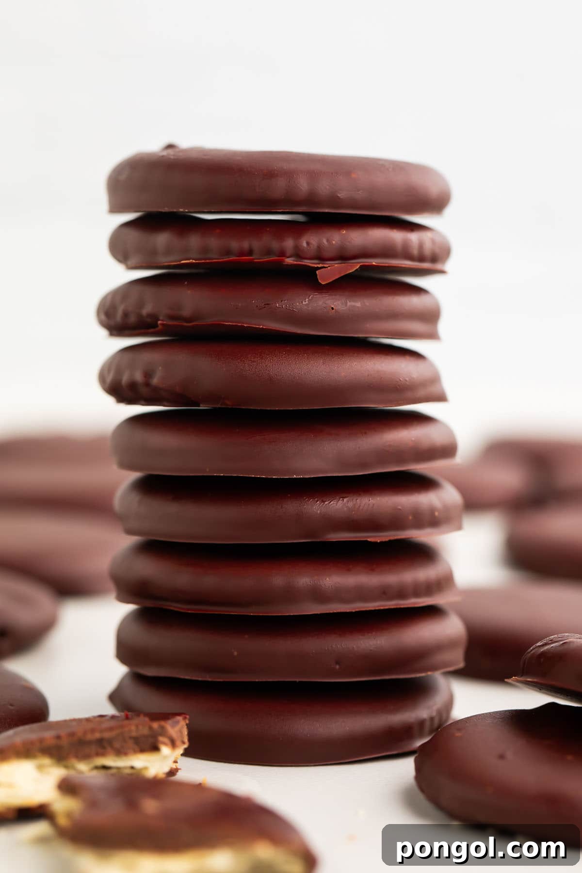 Classic Vegan Chocolate Mint Cookies 2 A tall stack of vegan thin mints on a table surrounded by other thin mint cookies.